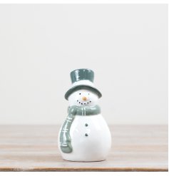 this freestanding snowman features a classic white body complemented by a soft sage green hat and matching scarf.