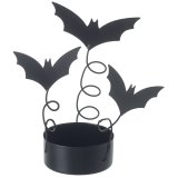 A striking Halloween decoration featuring three silhouetted bats perched above a metal t-light holder.