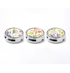 A compact metal pill box featuring the Wings & Wildflowers artwork by Jan Pashley.