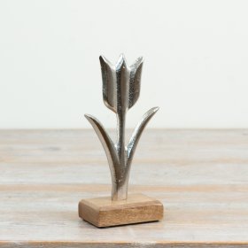 Refined aluminium tulip with a raw nickel finish resting on a natural wood base inspired by nature's elegance