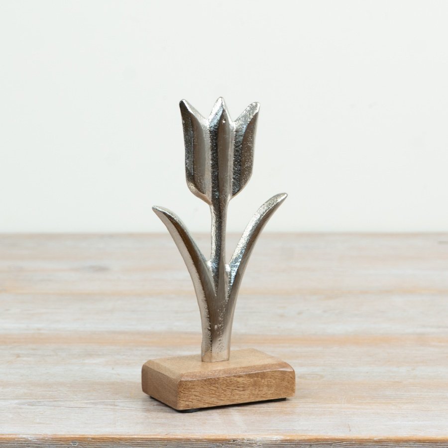 Refined aluminium tulip with a raw nickel finish resting on a natural wood base inspired by nature's elegance