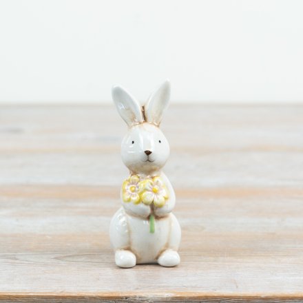 a charming standing glazed bunny rabbit holding a flowers 