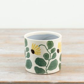 a delightful planter adorned with green leaves and a yellow sunflower motif