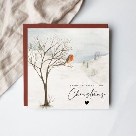 Charming watercolor artwork of a robin perched amid gently falling snow